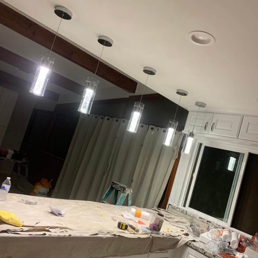 Electrician installing pendant lights over a kitchen island